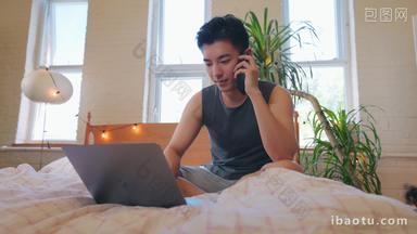 青年男人在家边用电脑边打电话